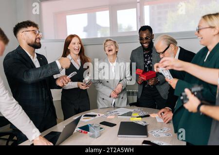 Happy multiethnic business team of mixed-aged diverse coworkers having fun, jumping, rejoicing from successful ending start-up project, scattering Stock Photo