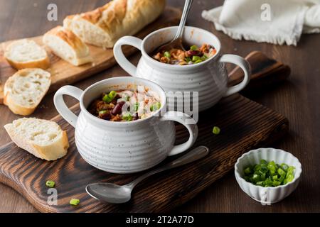 Soup crocks filled with homemade chili con carne, garnished with green onion. Stock Photo