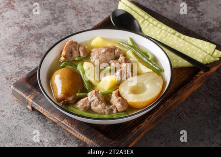 Lamb stew with pears, potatoes, green beans in a spicy sauce close-up in a bowl on a wooden board. horizontal Stock Photo