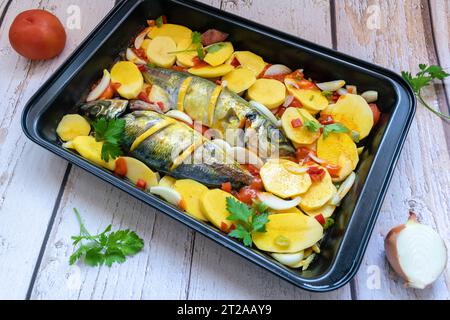 Delicious baked mackerel with potatoes and tomato, onion, lemon and spices in a dish Stock Photo