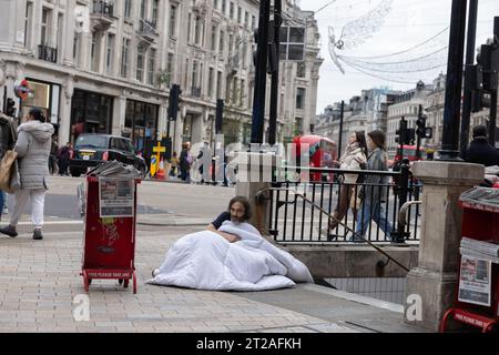 Homeless man, trying to keep warm outside Oxford Circus Underground station with a duvet whilst rough sleeping on the streets of London, England, UK Stock Photo