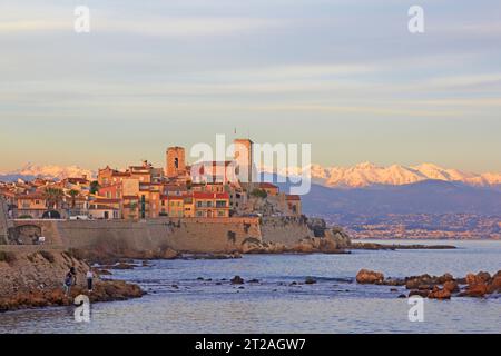 View of old Antibes showing the sea wall and the ramparts with the snow covered alpes maritimes in the background. Stock Photo