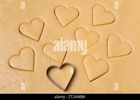 Heart shaped cookie cutters cutting out holiday. Cutting out heart shaped cookies from dough. Cooking a delicious healthy natural holiday breakfast fo Stock Photo