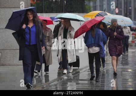 People walk through the rain in London, as storm Babet will bring heavy rain to the UK this week, with extensive flooding expected in already-saturated parts of Scotland. The Met Office has upgraded a weather warning for rain in eastern Scotland to amber, as some areas could see more than a month's worth of rain in a few days. Picture date: Wednesday October 18, 2023. Stock Photo