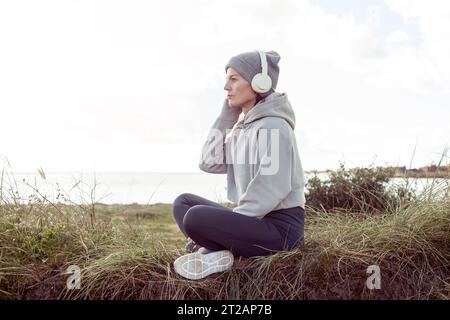 Sporty woman resting after exercise wearing headphones, outside. Stock Photo