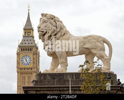 Close up of a large stone lion statue with the tower of Big Ben and clock in the background, Central London England UK Stock Photo