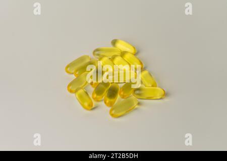 Omega-3-rich wild salmon and fish oil capsules presented on a soft off-white background. Stock Photo