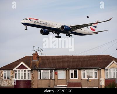 London Heathrow Airport Hounslow  British Airways Airbus A350-1041, aircraft on approach to landing low flying over residential housing with bird flying nearby Stock Photo