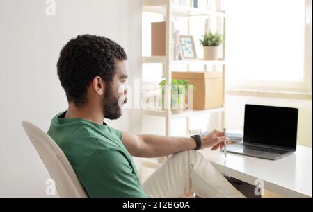 Focused young middle eastern man blogger or manager at table with laptop with empty screen Stock Photo