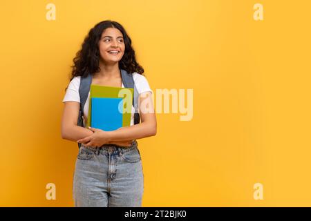 Smiling indian woman student holding notebooks looking at copy space Stock Photo