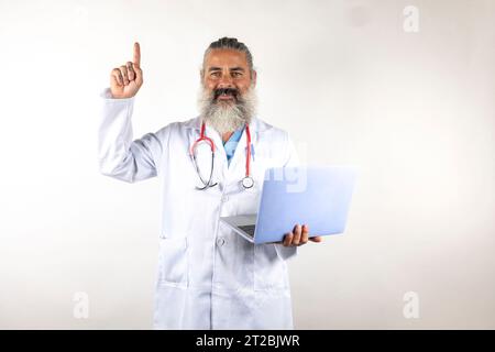 A doctor working with a laptop pointing his finger with a smiling face on a white background Stock Photo