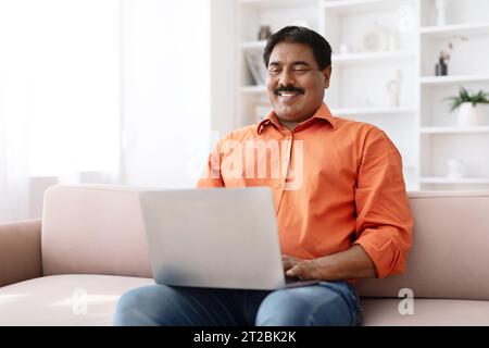 Cheerful middle aged indian man using computer lapotp at home Stock Photo