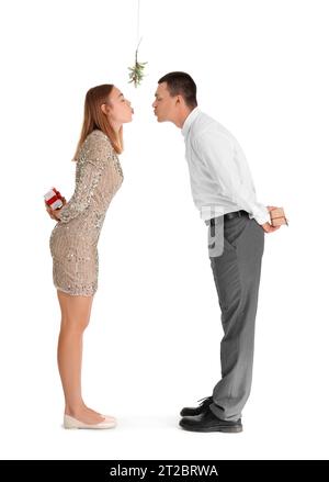 Young couple with Christmas gifts kissing under mistletoe branch on white background Stock Photo