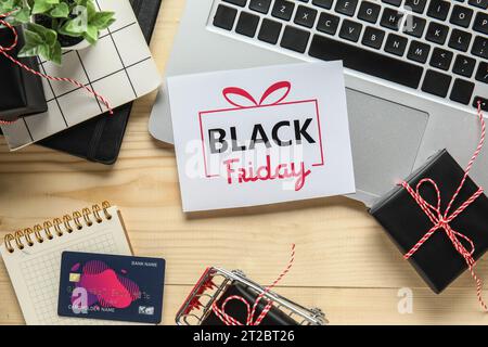 Black Friday sale greeting card with laptop, gift boxes and credit card on wooden table Stock Photo