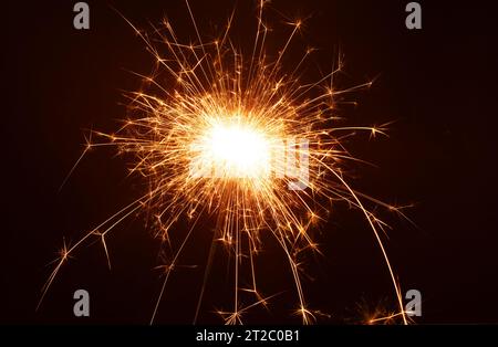 photo a close-up captures the fiery magic of a sparkler at a New Year's party. In the dark, it burns with brilliance, creating a close, celebratory at Stock Photo
