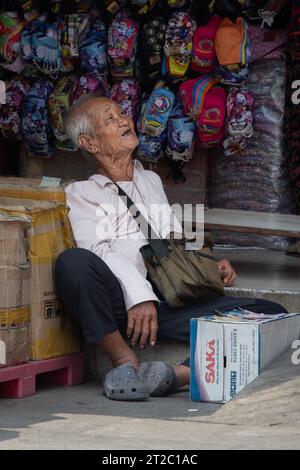 Old Vietnamese Man Sitting in Market Stock Photo