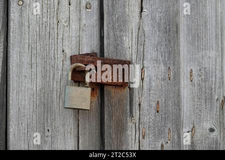 I warn brass padlock and a rusty has Guard and old weathered door Stock Photo