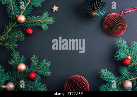 Christmas frame made of fir branches with Christmas balls on black background. Top view, flat lay, copy space. Stock Photo