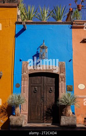 A colorful blue wall and Spanish Colonial style wooden door on a home in the historic city center of San Miguel de Allende, Mexico. Stock Photo