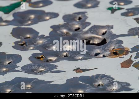 bullet holes in the metal. multiple bullet marks on the car body. peeling green. bullet holes, texture, metal, shooting, shooting on the street, shot, Stock Photo