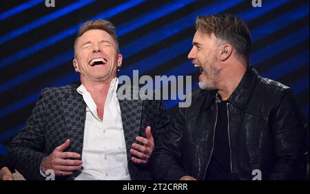 Leipzig, Germany. 18th Oct, 2023. Irish singer Ronan Keating (l) and Gary Barlow from the British pop group Take That laugh together in the 'Your Songs' show in Leipzig. Mitteldeutscher Rundfunk recorded the music show with big names. The artists perform their big hits alongside new songs in a live atmosphere, accompanied by a studio band and the 40-piece MDR Symphony Orchestra. On December 15, 'Your Songs' will be broadcast on the German public broadcaster Ersten and will be available in advance in the Mediathek from December 8. Credit: Hendrik Schmidt/dpa/Alamy Live News Stock Photo