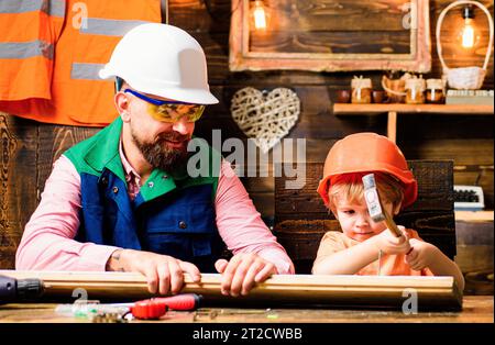 Father and son hammers nails with a hammer in a wooden board. Happy fatherhood. Stock Photo