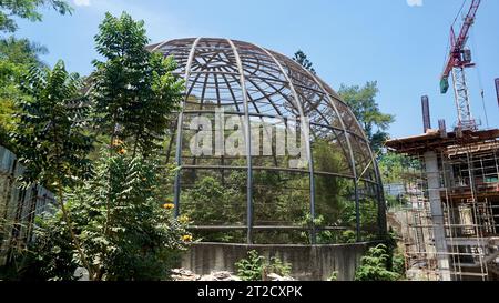 Large metal dome aviary for bird conservation next to a building construction site Stock Photo