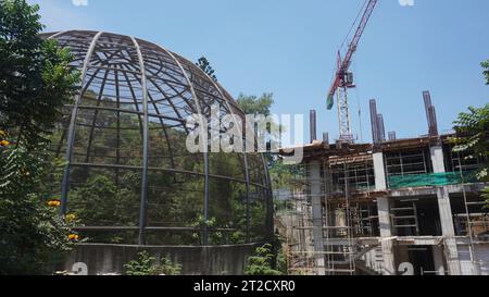 Large metal dome aviary for bird conservation next to a building construction site Stock Photo