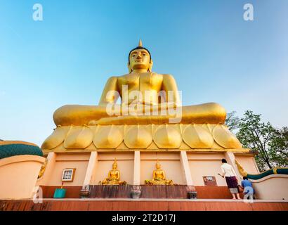 Steps lead up to the beautiful, vibrant gold image of the Buddha,reflecting light from the setting sun,popular holy site and tourist attraction overlo Stock Photo