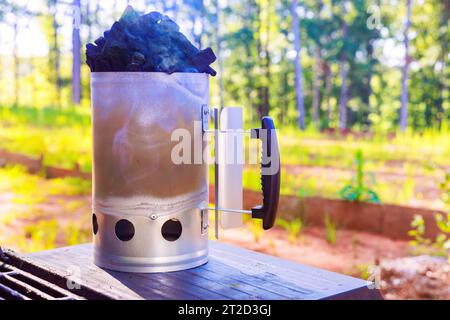 BBQ chimney starter is used to get charcoal ready for grill so that it is glowing hot when you turn it on Stock Photo