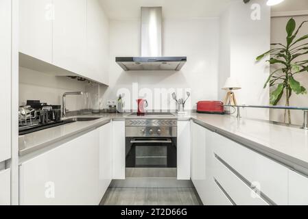 https://l450v.alamy.com/450v/2t2d66g/open-kitchen-of-a-loft-style-apartment-with-bright-white-furniture-arranged-in-a-u-shaped-format-with-integrated-stainless-steel-appliances-2t2d66g.jpg