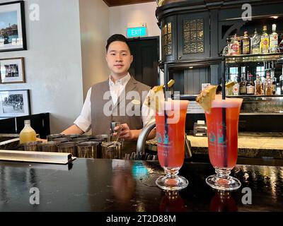 PRODUCTION - 03 October 2023, Singapore, Singapur: A bartender mixes original Singapore Slings at the world-famous Long Bar at Raffles Hotel. It was here that bartender Ngiam Tong Boon invented the gin-based cocktail in 1915. The high-proof drink looks like a fruit juice so the ladies could follow etiquette. (to dpa 'From the Ritz to Harry's Bar: Where 'Classic Cocktails' Became Legends') Photo: Carola Frentzen/dpa Stock Photo