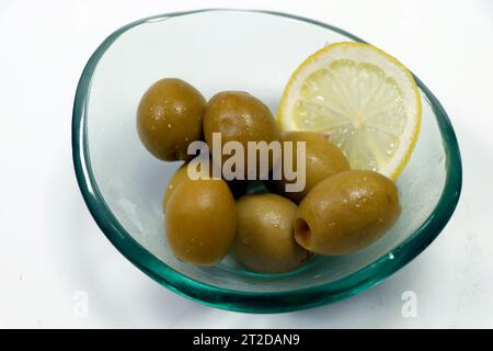 pitted greek green olives in a glass bowl with white background Stock Photo
