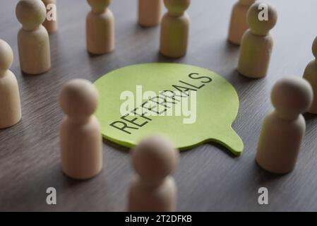 A group of wooden figurines surrounding a speech bubble with text REFERRALS. Recommendation, marketing, customer retention and loyalty concept Stock Photo