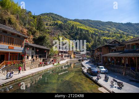 TULOU CLUSTER, FUJIAN, CHINA. FEBRUARY 17th, 2021: The small houses in the Tuxi village around Tulou clusters and the river in between, Blue sly, copy Stock Photo