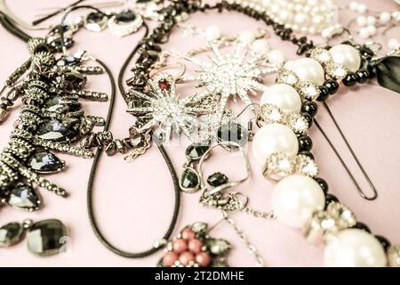 Beautiful precious shiny jewelery trendy glamorous jewelry set, necklace, earrings, rings, chains, brooches with pearls and diamonds on a pink purple Stock Photo