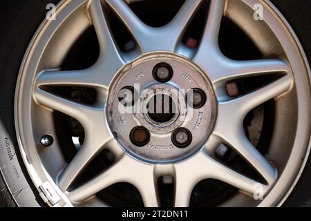 Used car alloy wheel with spokes and visible bolts. Close up shot, no people, natural light. Stock Photo