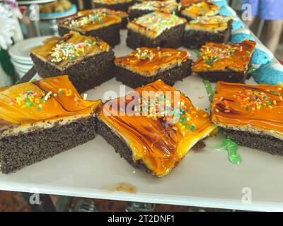 sweets on the table in the hotel. chocolate cake with caramel topping. appetizing multi-colored cakes with sugar sprinkles. dessert with berry and fru Stock Photo