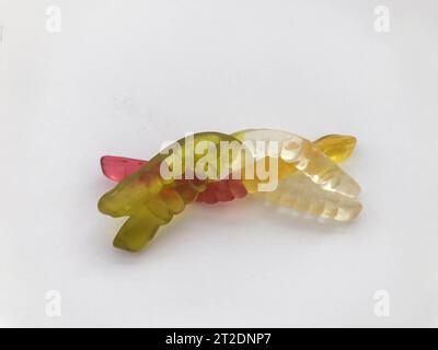 gelatinous delicious gummy worms. delicious appetizing dessert. white-green and red-yellow worm intertwined on a white matte background. Stock Photo