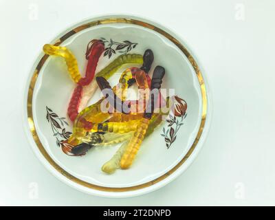 Bright delicious beautiful juicy multi-colored gelatinous gummy sweet candies worms lie in a glass plate. Sweet dessert for children. Stock Photo