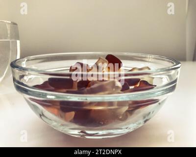 Bright tasty beautiful juicy multi-colored gelatinous gummy sweet candies soda bottles lie in a glass plate. Sweet children's dessert delicacy. Stock Photo