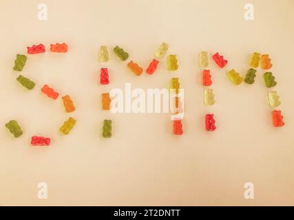 letter from multi-colored gummy bears. Letter S and M made from gelatinous candies on a matte orange background. edible word SMM. marketing of gummies Stock Photo