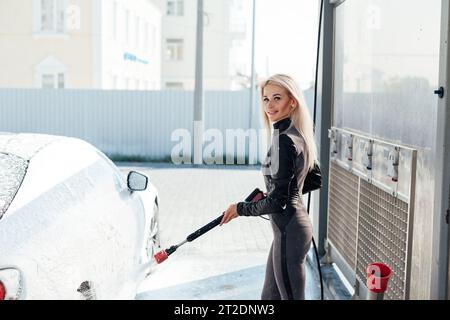 Beautiful woman washing car at car wash dry cleaning Stock Photo
