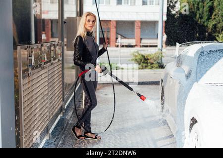 Beautiful woman washing car at car wash dry cleaning Stock Photo