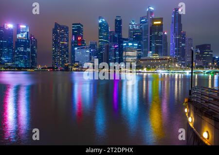 A night view of Marina Bay and the city skyline in Singapore, seen from the boardwalk promenade of the Esplanade Theatre Precinct. Stock Photo