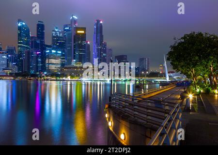 A night view of Marina Bay and the city skyline in Singapore, seen from the boardwalk promenade of the Esplanade Theatre Precinct. Stock Photo