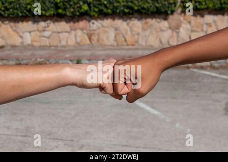 Hands of different ethnicities, African and European, bumping fist to fist in a concept of friendship or camaraderie Stock Photo