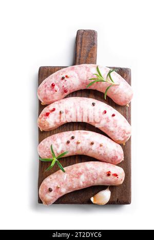 Raw Sausages with rosemary and spices on wooden cutting board isolated on white backgrund. Stock Photo