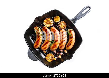 Grilled sausages with garlic and herbs on cast iron grill pan isolated on white background,  top view. Roasted homemade german wurst sausages. Stock Photo