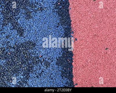 Blue and red texture of the soft rubber surface of the safe cover of the sports playground for workout made of pressed fine rubber. Stock Photo